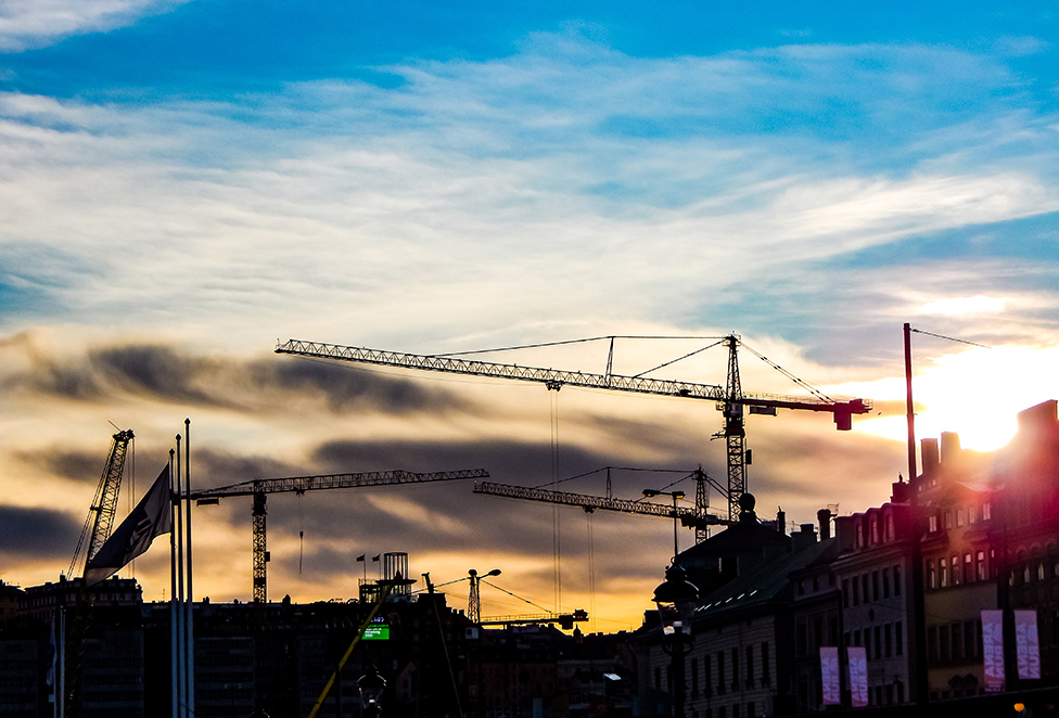 Siluetter av byggkranar i solnedgång över Stockholm