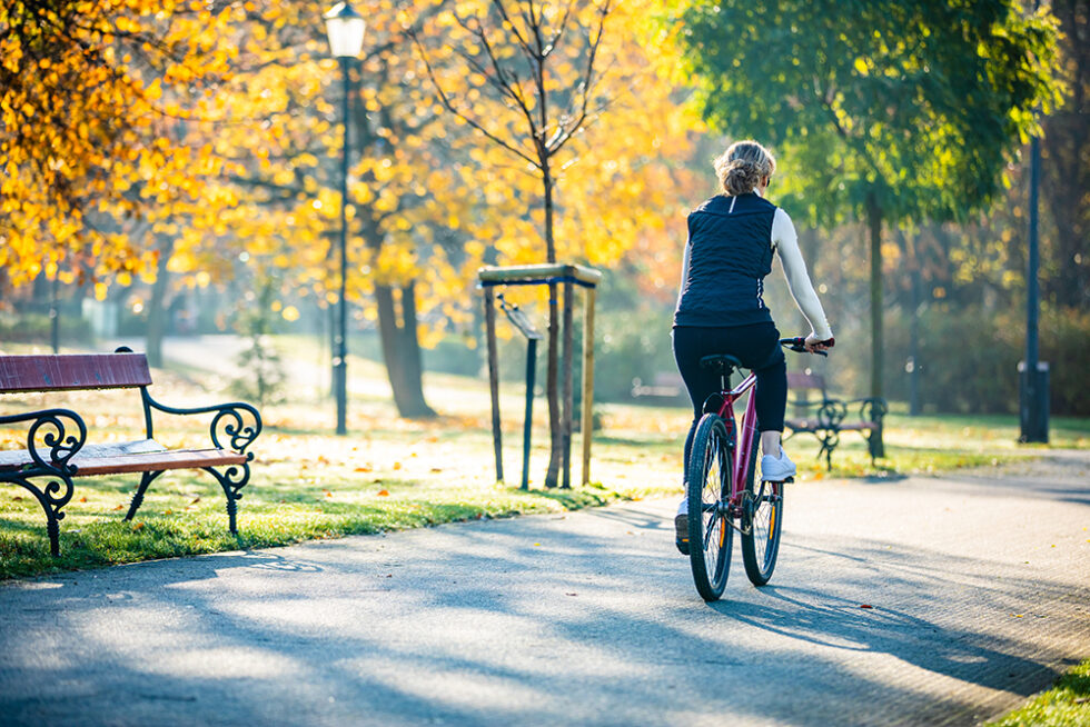 kvinna som cyklar i en park med höstfärger