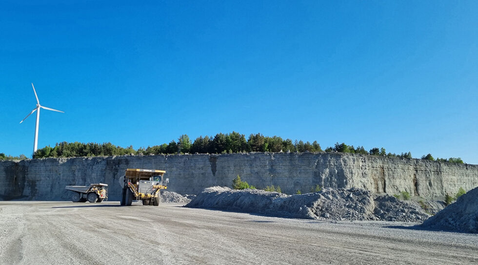 Kalkstenstäkten i Slite. Två dumprar kör material och en vindkraftsnurra syns i bakgrunden.