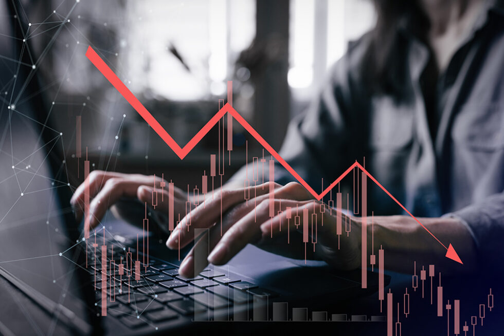 Man som sitter vid laptop och över hela fotot ligger ett linjediagram i rött som pekar nedåt.