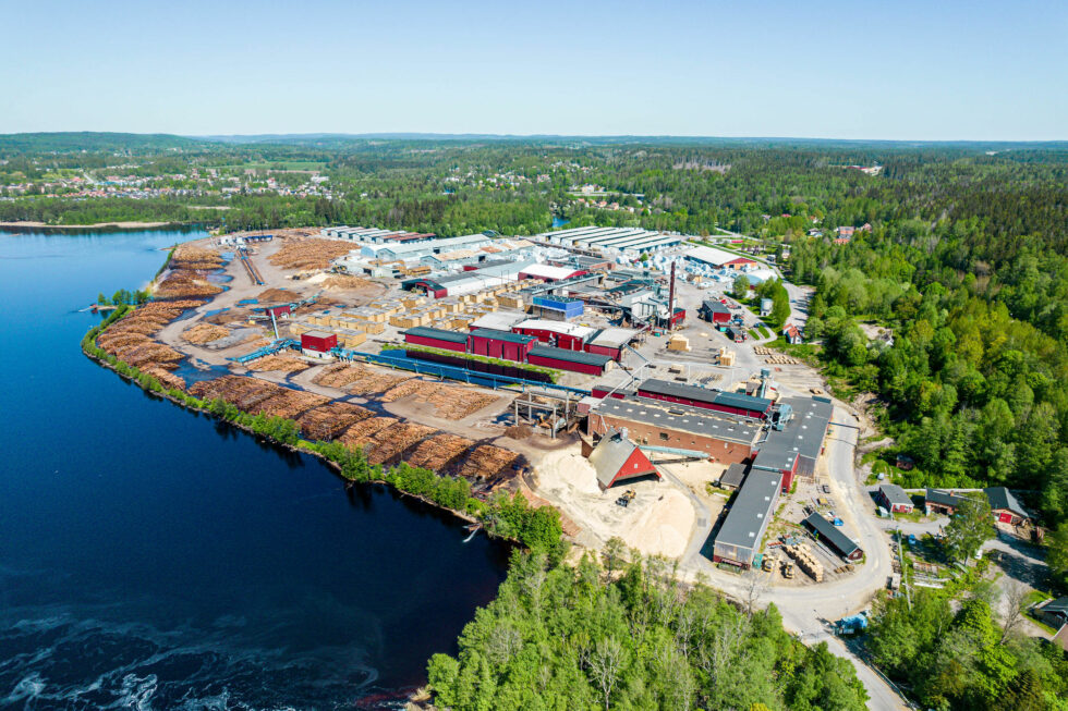 Flygfoto över Moelvens sågverk i Valåsen, Karlskoga. Fabriksområde ligger vid en sjö med skog runt omkring.