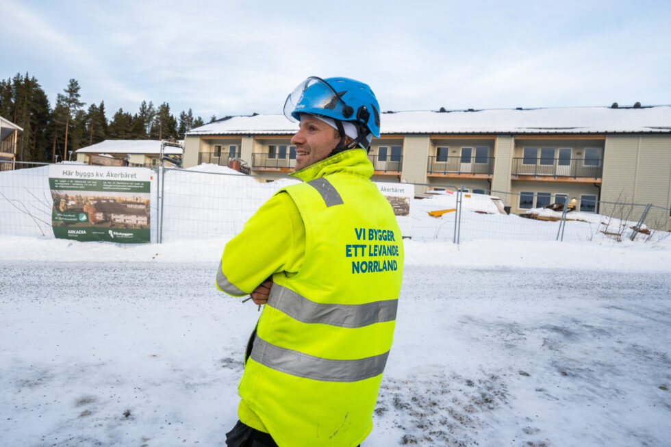 Man i varselkläder och hjälm som syns i profil framöver ett pågående bygge i Skellefteå.