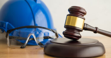 Blå bygghjälm med skyddsglasögon framför, samt en domarklubba bredvid.
