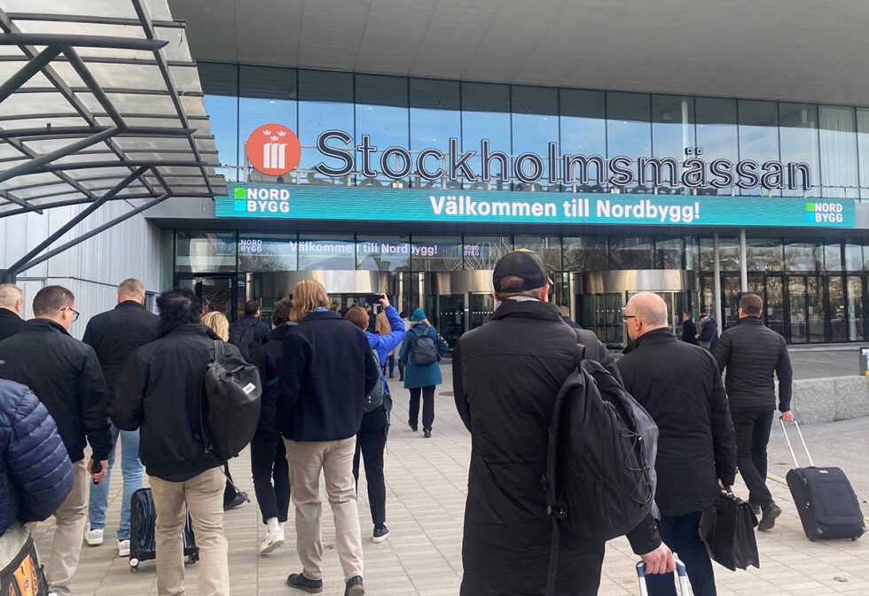 Flera personer på väg in genom Stockholmsmässans entré. Över dörrarna syns en stor skylt med texten välkommen till Nordbygg