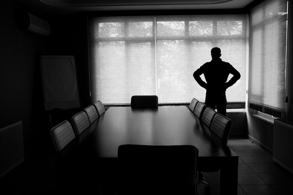 svartvit foto som visar en siluett av en person som står i ett mötesrum