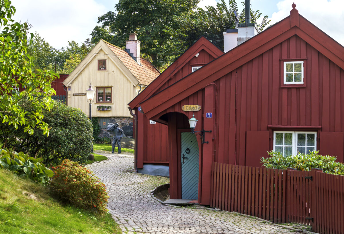 Två röda låga timmerhus med en stengång bredvid.