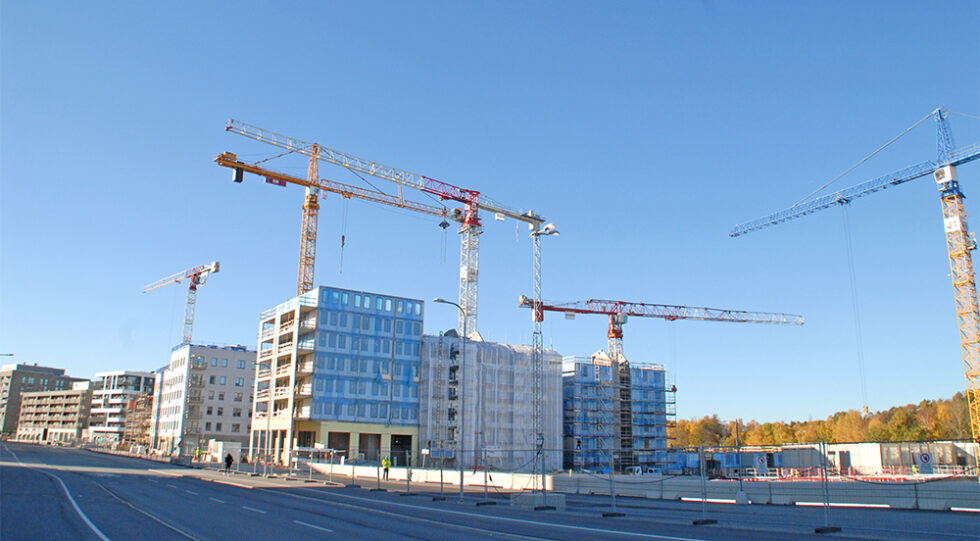 pågående bygge av flerbostadshus. Blå himmel och byggkranar.