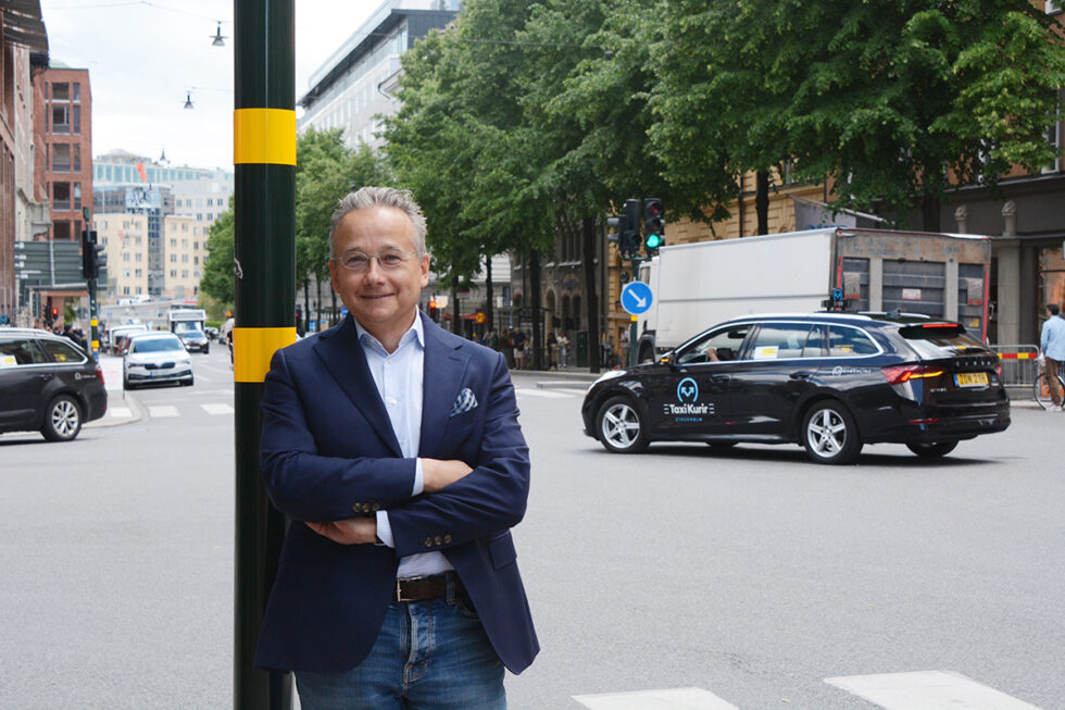 Joachim Hallengren står lutad mot en stolpe för trafikljus i en vägkorsning på Söder i Stokcholm.