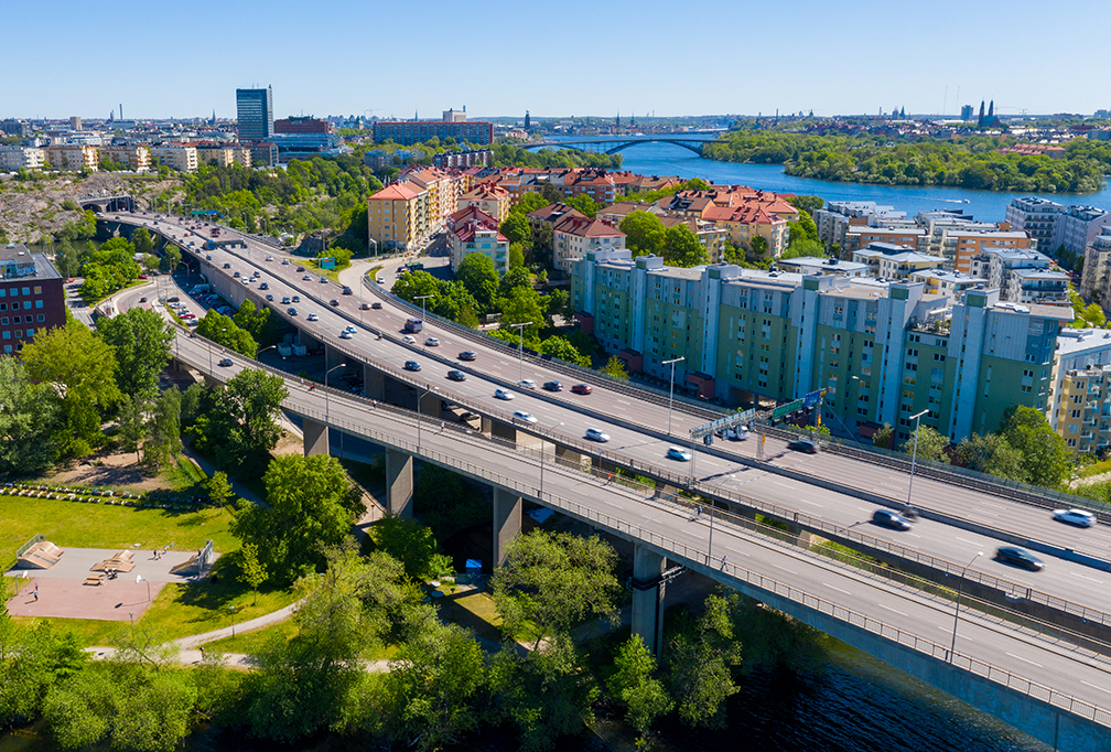 Förenklade regler för trafikbuller vid bostäder ska utredas. Fotot visar Essingeleden med trafik och bostäder